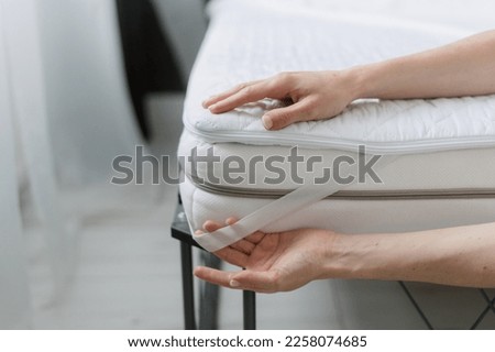 cropped shot of female hands put clean mattress topper with elastic band on corners on bed at home bedroom, protection surface, comfort sleeping concept Royalty-Free Stock Photo #2258074685
