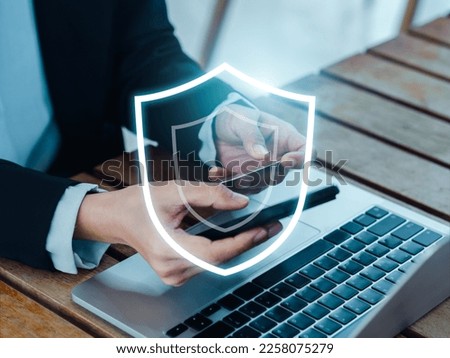 Secure payment concept. The large shield icon glowing while business people using mobile smart phone purchase and credit card in hand for online shopping, digital banking transaction, finance app.