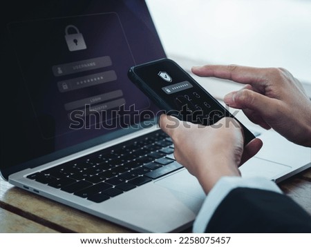 Two steps authentication (2FA) concept. Shield icon and password code showing on smart phone screen while businessperson login on laptop computer, Identity verification, cybersecurity technology. Royalty-Free Stock Photo #2258075457