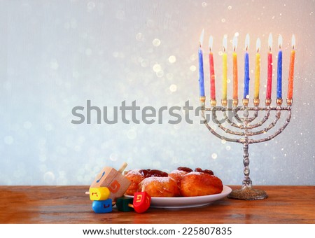 Image of jewish holiday Hanukkah with menorah, doughnuts and wooden dreidels (spinning top)