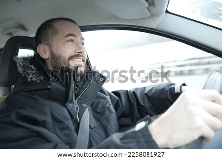 A happy young man driving a car with a big smile on his face, enjoying the trip