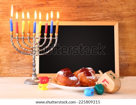 jewish holiday Hanukkah with menorah, doughnuts over wooden table. retro filtered image 