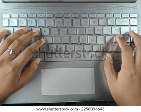 someone's hand is typing on the laptop keys with beautiful fingers