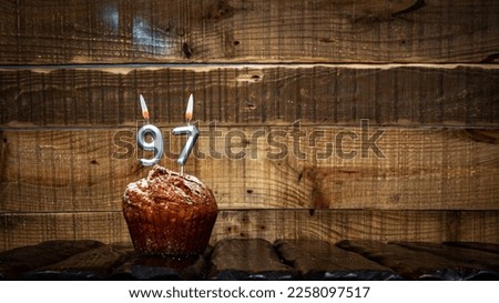 Background happy birthday pie or muffin with candles burning digit number  97. Festive card Happy Birthday on the background of vintage boards. Anniversary copy space