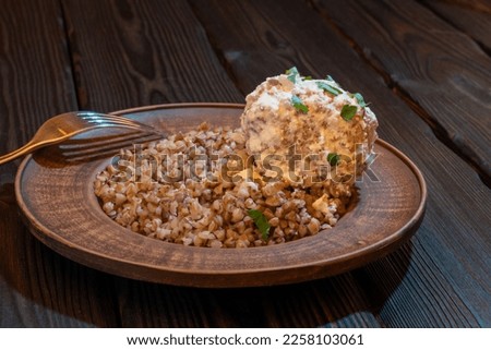 Buckwheat porridge with meatballs with cream sauce on a plate. Background picture.