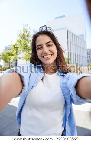 Vertical selfie of a Young beautiful woman smiling at university campus. Trendy girl in casual attire. Positive cheerful female student posing outdoors for sharing in social media app. Caucasian lady
