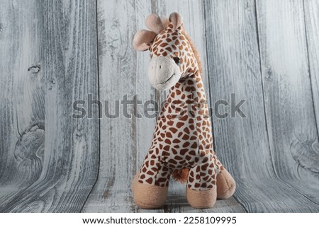 Giraffe plush doll isolated on grey background with shadow reflection. Giraffe plush doll on white background. Colorful plush toy. Colored stuffed toy-giraffe. White brown giraffe