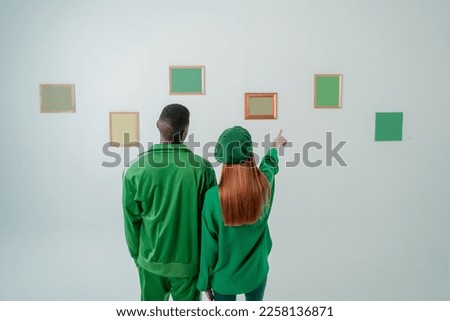 couple looking at photo frames on wall green screen 