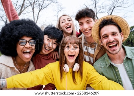 Multiracial group of happy friends taking a mobile selfie in urban park. Positive international teenagers taking a photo while strolling down the street in autumn. Big smiles and good times. 