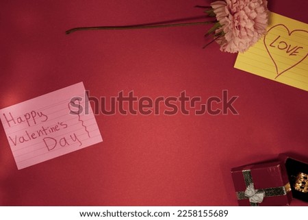 Flower with a Noteand Gift Box thet says Happy Valentine's Day on a Pink Red Background Flat lay. Top view. Copy space - Image