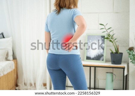Back pain, kidney inflammation, woman suffering from backache at home, painful area highlighted in red, BeH3althy concept photo