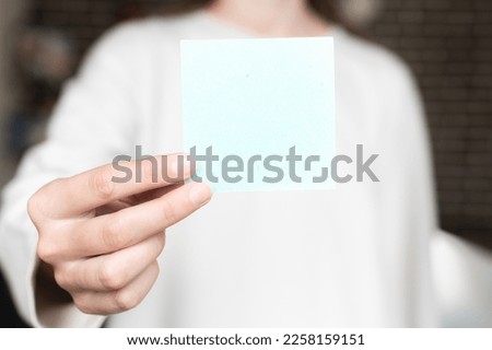 woman is holding a square empty blank sticker in her hands. Background space for text or advertising or reminder