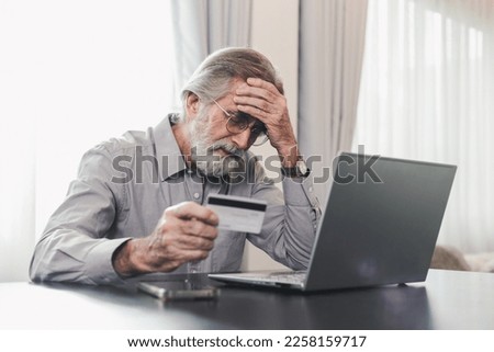 Upset senior elderly man holding credit card by laptop having trouble worry finance safety data or online payment security. Bank client concerned about problem with credit card, financial fraud threat Royalty-Free Stock Photo #2258159717