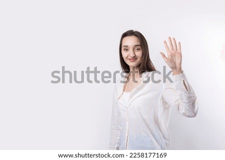 Smiling woman raised her hand palm up and forward like waving.