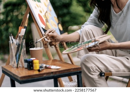 Female artist painting art canvas drawing with inspiration in garden art therapy creativity concept.
