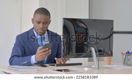 African-American Businessman Working on Smartphone and Computer