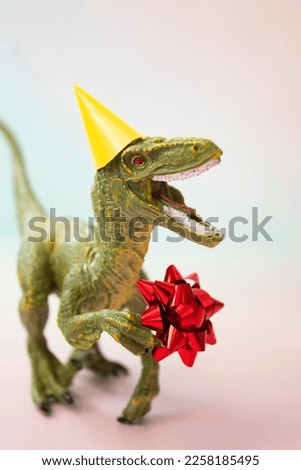 A Tyrannosaurus in a festive yellow birthday hat with a gift in its paws on a light background. A festive greeting card with Women's Day, mother's Day, birthday is a creative minimalistic concept.