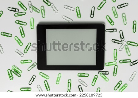 Tablet Screen With Important Ideas On It And green paperclips On Desk around the device. Cellphone With Crutial Informations And Memo Attached To It.