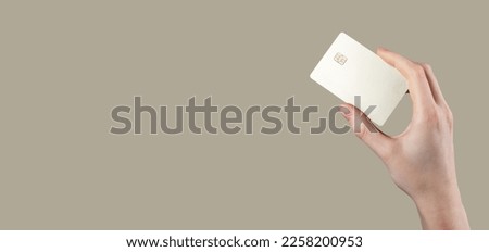 Bank card mock up in hand. Blank debit plastic bankcard with chip of gold color between fingers on background, ad banner. High quality photo