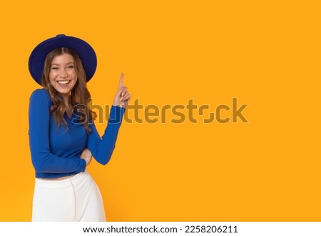 Happy woman with blue hat and elegant clothes on isolated orange background.