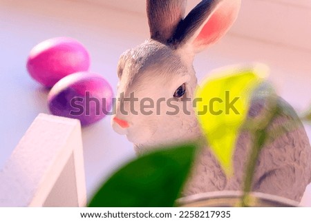 Head ceramic easter rabbit next to red eggs. Close-up blurred plan, festive background. Easter concept.