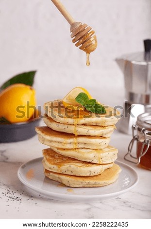Stack of Pancakes with lemon flavor and poppy seeds, served with honey. Healthy breakfast for the family. 
