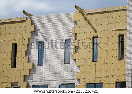 Sheathing of the outer wall of a brick building with insulation. Insulation of the facade of the building. The concept of exterior finish, moisture protection,sound insulation,energy saving. Royalty-Free Stock Photo #2258226421