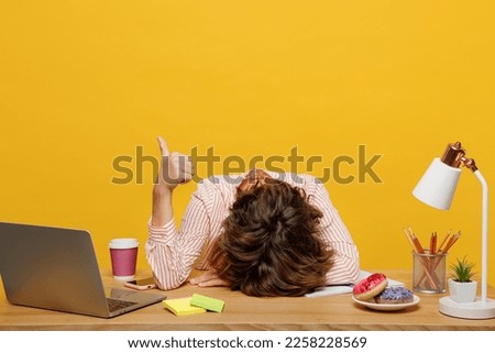 Young sleepy employee business woman wear casual shirt sit work at office with pc laptop put head down on desk sleep show thumb up isolated on plain yellow color background Achievement career concept Royalty-Free Stock Photo #2258228569