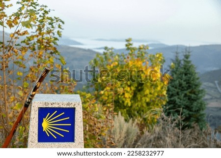stone post with scallop shell Camino de Santiago symbol with landscape Galicia mountain view at O Cebreiro