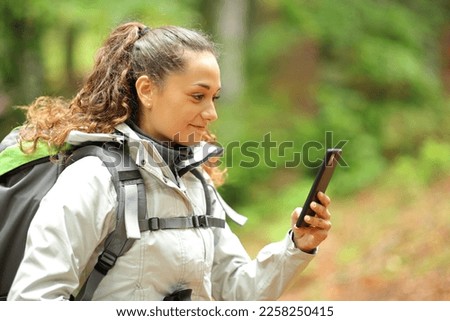 Hiker walking checks phone in a forest