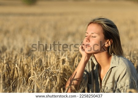 Relaxed woman in a field at sunset resting Royalty-Free Stock Photo #2258250437