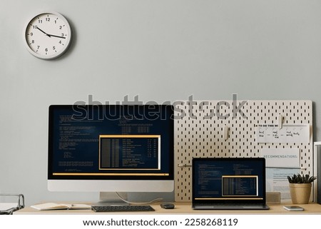 Front view office workplace setup with computer code on two screens, copy space