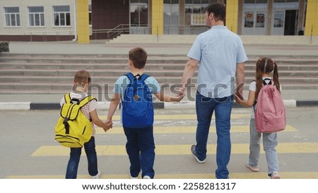 father leads children to school through pedestrian crossing. happy family. zebra road. group child girl boy go to school with school backpacks. happy family concept. school students. parent with kid