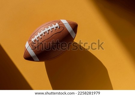 American football leather ball on yellow background. Top view. Game equipment horizontal sport theme poster, greeting cards, headers, website and app Royalty-Free Stock Photo #2258281979