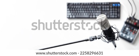live stream, live talk, voice recording, webinar, concept.  A large condenser microphone in a mic holder on a stand. with PC and mixer on the table. shallow depth of field.