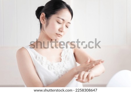 Woman applying body cream (troublesome) Royalty-Free Stock Photo #2258308647