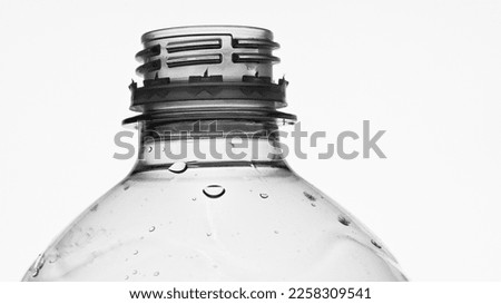 detailed monochrome closeup against the light of the screw thread of a plastic water bottle with some water drops
