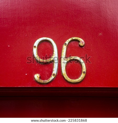 metal house number ninety six on a red lacquered background.