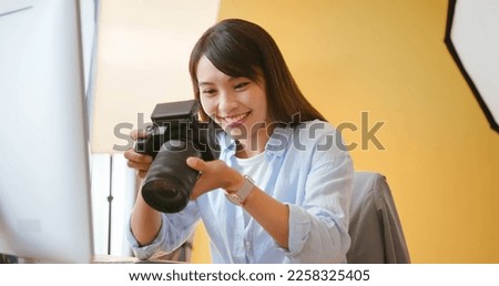 asian female photographer is checking up color of pictures in digital camera and she satisfied with the work