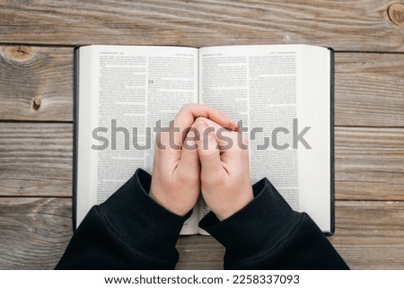 Close-up, christian read Bible. Hands folded in prayer on a Holy Bible, on wooden background, top view.