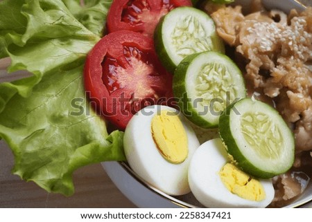 
product photo of rice bowl with tomatoes, cucumber and lettuce vegetables, complemented by savory chicken