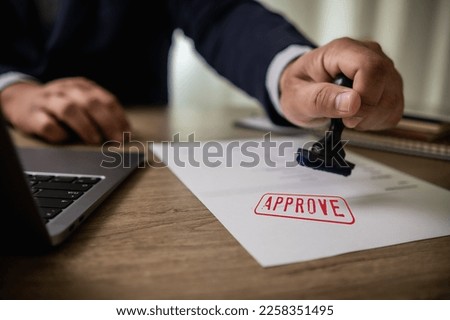 man stamping approval Text is approved by stamping the document on paper.