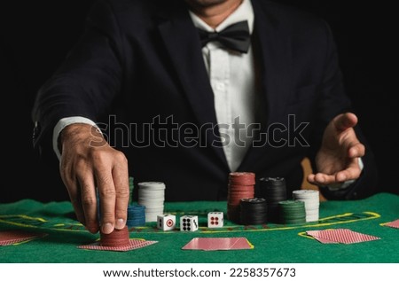 Crop picture of close up man dealer or croupier shuffles poker cards betting holding chips in casino of green table, Dealer man invitation bet playing cards. Casino, poker, poker game concept.