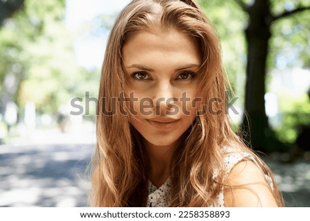 Selfie, portrait and woman at a park, content and calm against bokeh background space. Face and serious freedom, travel and peaceful trip for lady posing for photo while relaxing in nature