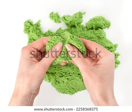 Green kinetic sand in hands on a white background. Sand molding.