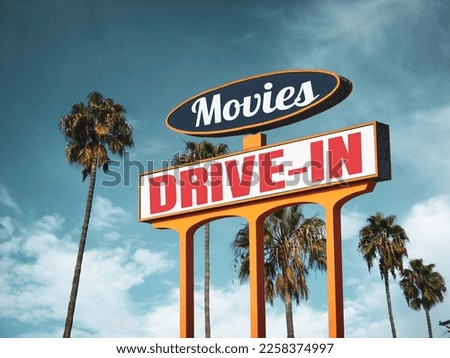 Aged and worn vintage drive-in movies sign with palm trees                               
