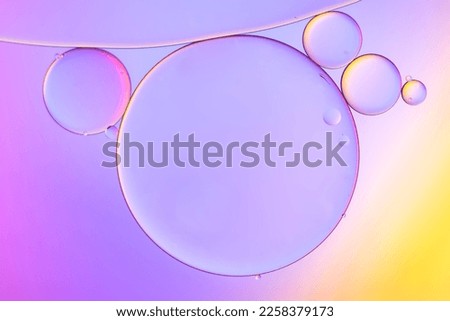 Top view movement of oil bubbles in the liquid. Oil surface multicolored background. Fantastic structure of colorful bubbles. Colorful artistic image of oil drop floating on the water Royalty-Free Stock Photo #2258379173