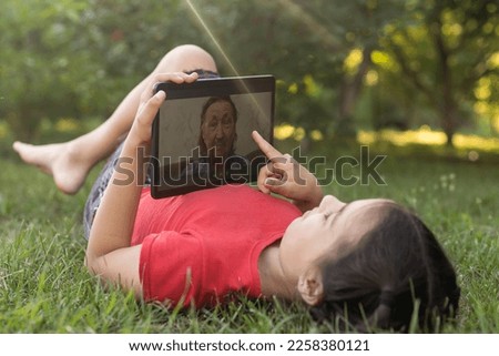 Child girl playing on a Digital tablet in the garden. Online or Remote education concept