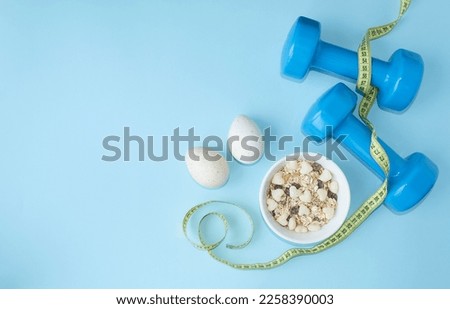 Sports lifestyle, balanced diet.  On a blue background, blue dumbbells, a centimeter, diet food, proteins, carbohydrates.  The concept of diet, proper nutrition.  Flat lay.  Space for copy text.