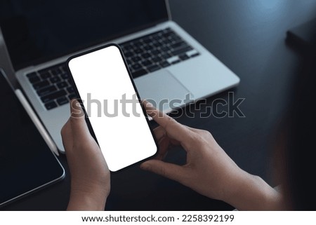 Mockup, blank screen cell phone. women hand holding, using mobile phone, working on laptop computer at  office. white empty space for advertisement. contact business, web template or mobile app design